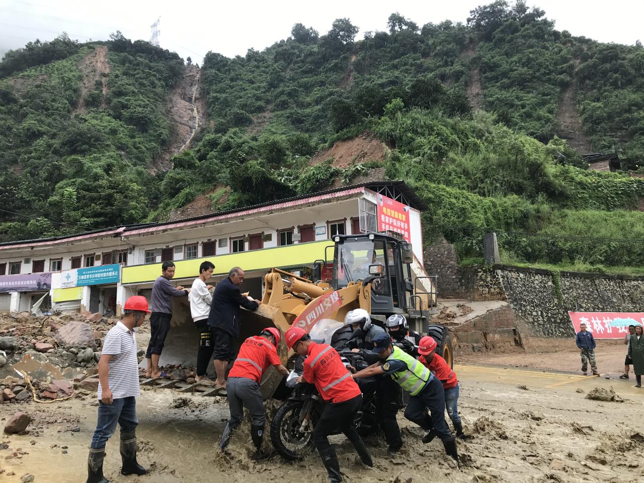 8月18日，搶險(xiǎn)人員與民警幫助被困群眾的摩托車通過涉水路面.jpg